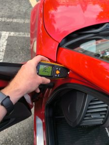 Medidor de espesor con lectura de 345 micras en el marco delantero de un BMW durante una revisión de carrocería.