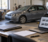 Vehículo en un taller junto a documentación y un ordenador con ofertas de coches